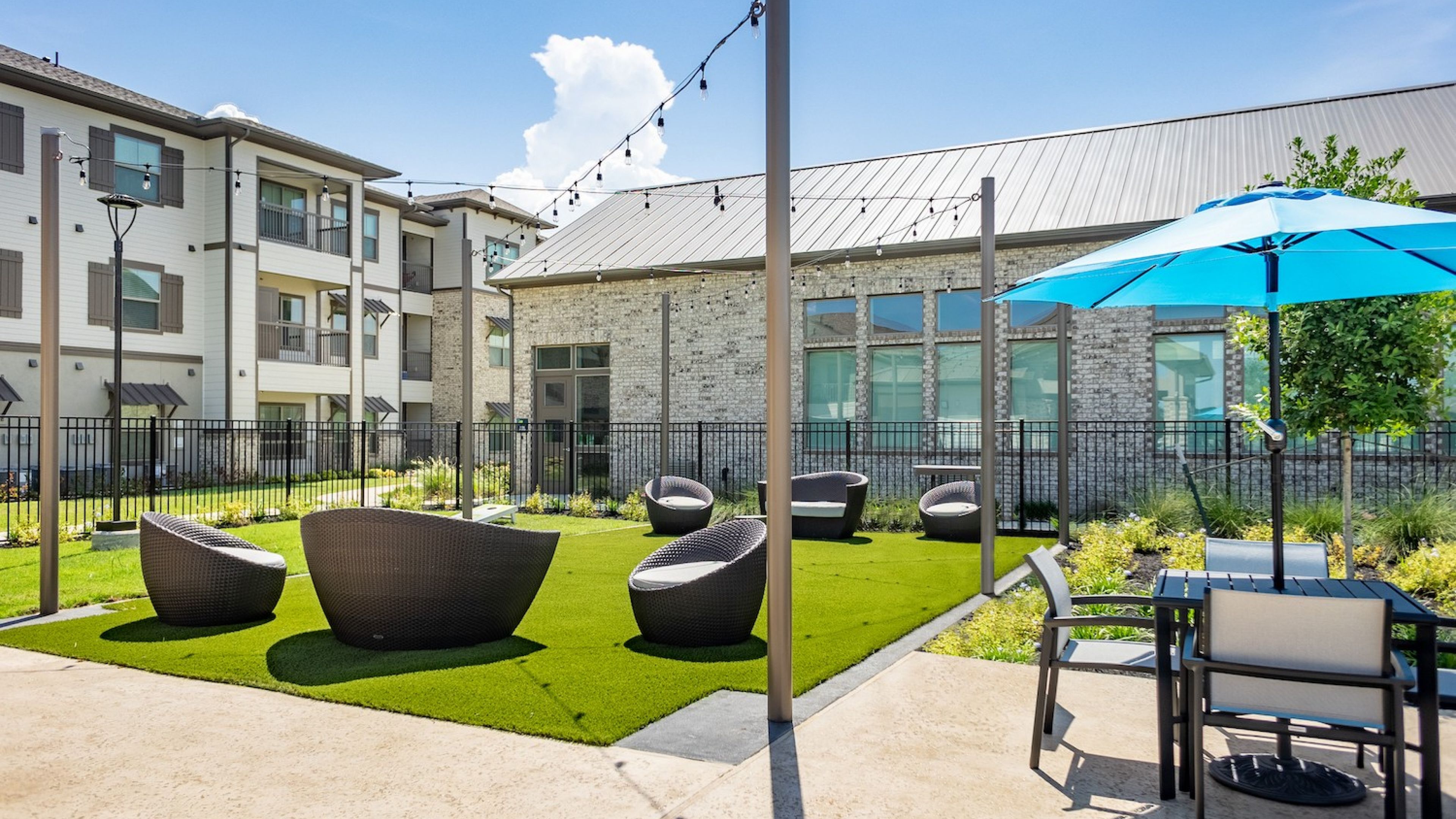Hawthorne at Bay Forest apartments community exterior with outdoor hangout spot, lawn games, and picnic area